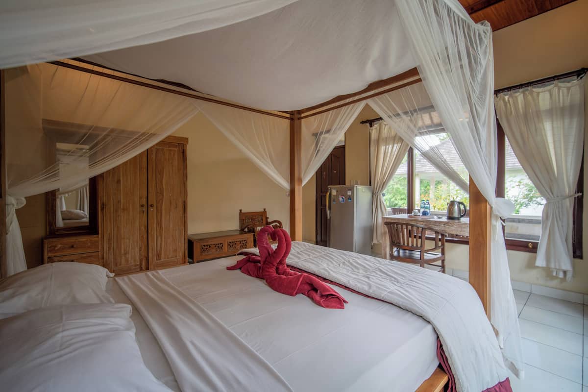 A bedroom with a canopy bed, wooden furniture, and a view of the outdoors.