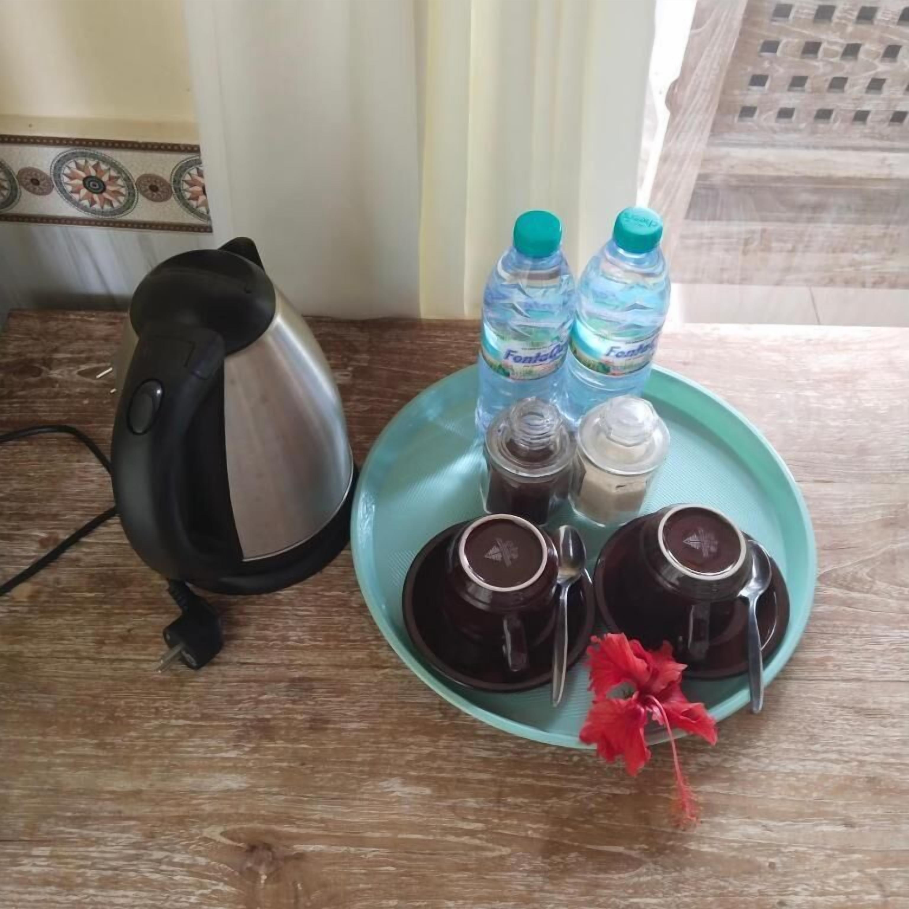 A kitchen area with a kettle, two water bottles, and two coffee cups on a tray.