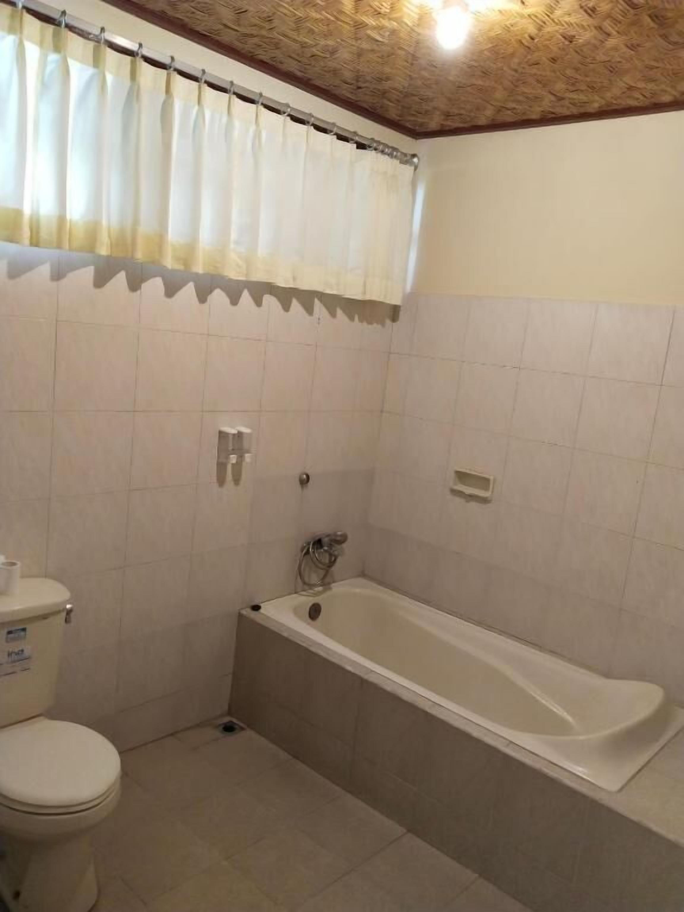Casa de banho com sanita, banheira e paredes revestidas a azulejos.