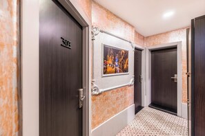 A hallway with a framed picture, dark wooden doors, and a patterned floor. - Taksim Terrapia Hotel (Istanbul)