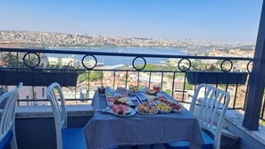 A balcony with a table set for a meal, overlooking a cityscape and a body of water. - Taksim Terrapia Hotel (Istanbul)