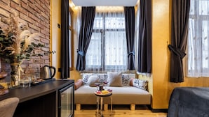 A cozy room with a sofa, a small table with drinks, and a decorative plant. - Taksim Terrapia Hotel (Istanbul)