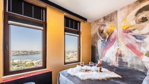 A room with a bed, two windows with city views, a table with wine glasses, and a painting on the wall. - Taksim Terrapia Hotel (Istanbul)