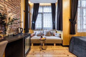 A cozy room with a sofa, a small table with drinks, and a decorative plant. - Taksim Terrapia Hotel (Istanbul)