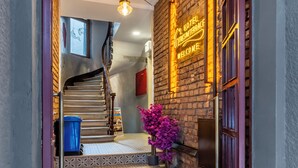 A hotel entrance with a red doormat, a staircase, a neon sign, and a brick wall. - Taksim Terrapia Hotel (Istanbul)