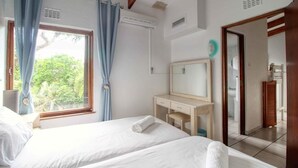 A hotel room with two beds, a desk, a mirror, and a window with curtains. - Top Destinations (Southbroom)