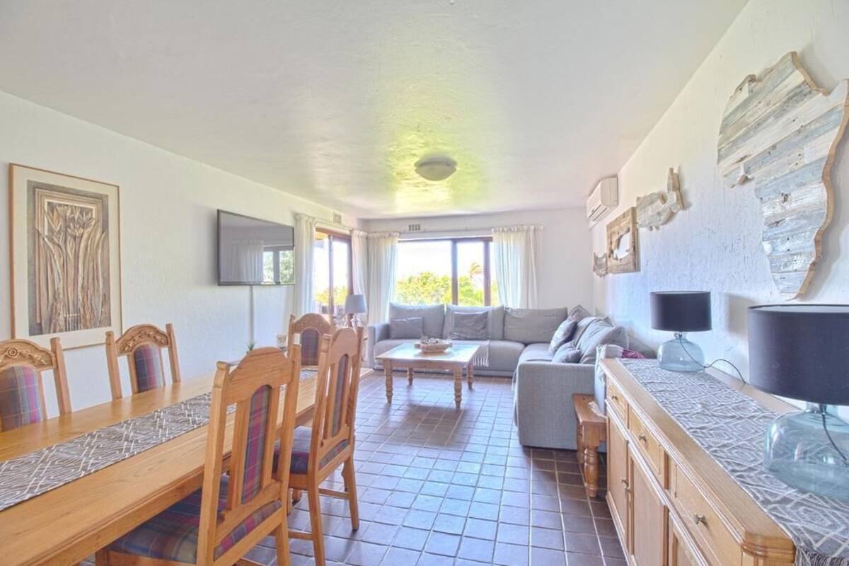 Un coin repas avec une table et des chaises en bois, un canapé et un téléviseur fixé au mur.