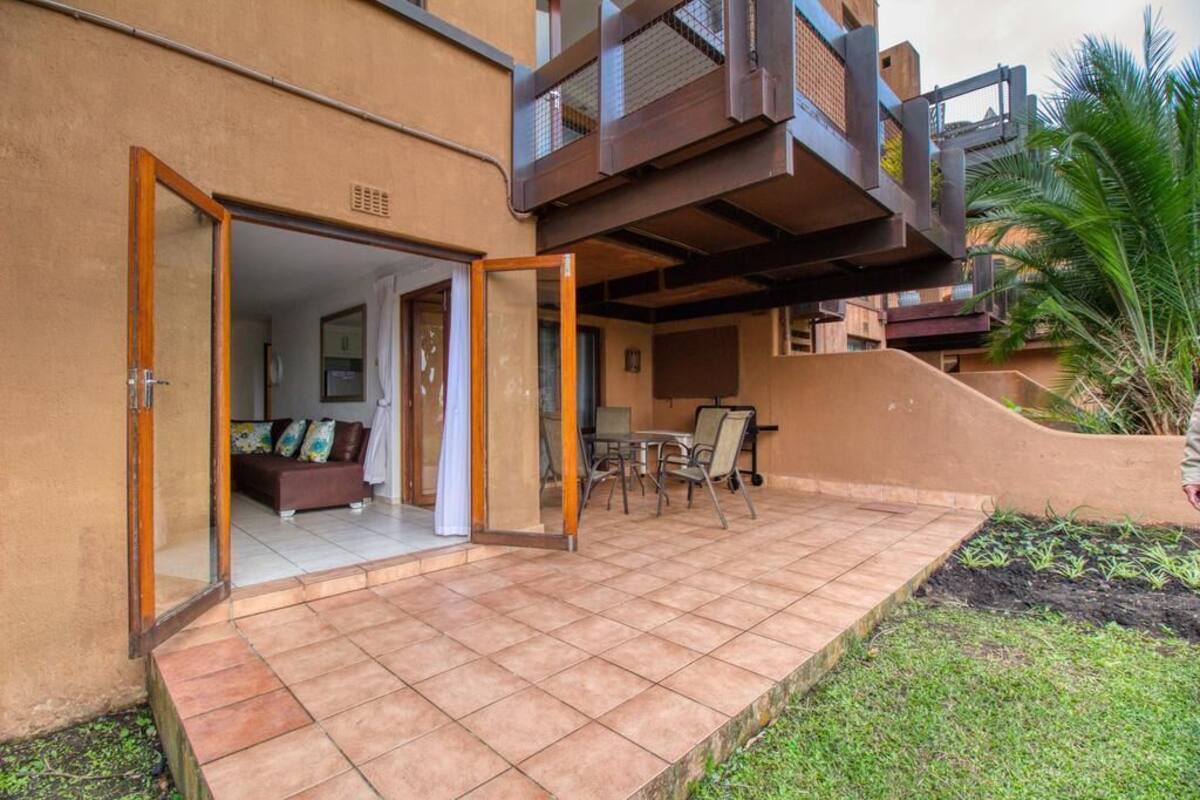 Un espace extérieur aménagé en terrasse, doté d’un sol carrelé, de sièges et offrant une vue sur l’intérieur.