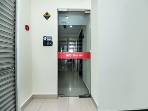 A hotel entrance with a surveillance sign, a fire alarm, and a sign indicating the OYO Stay Inn. - OYO 89965 Stay Inn Ii (Kota Kinabalu)
