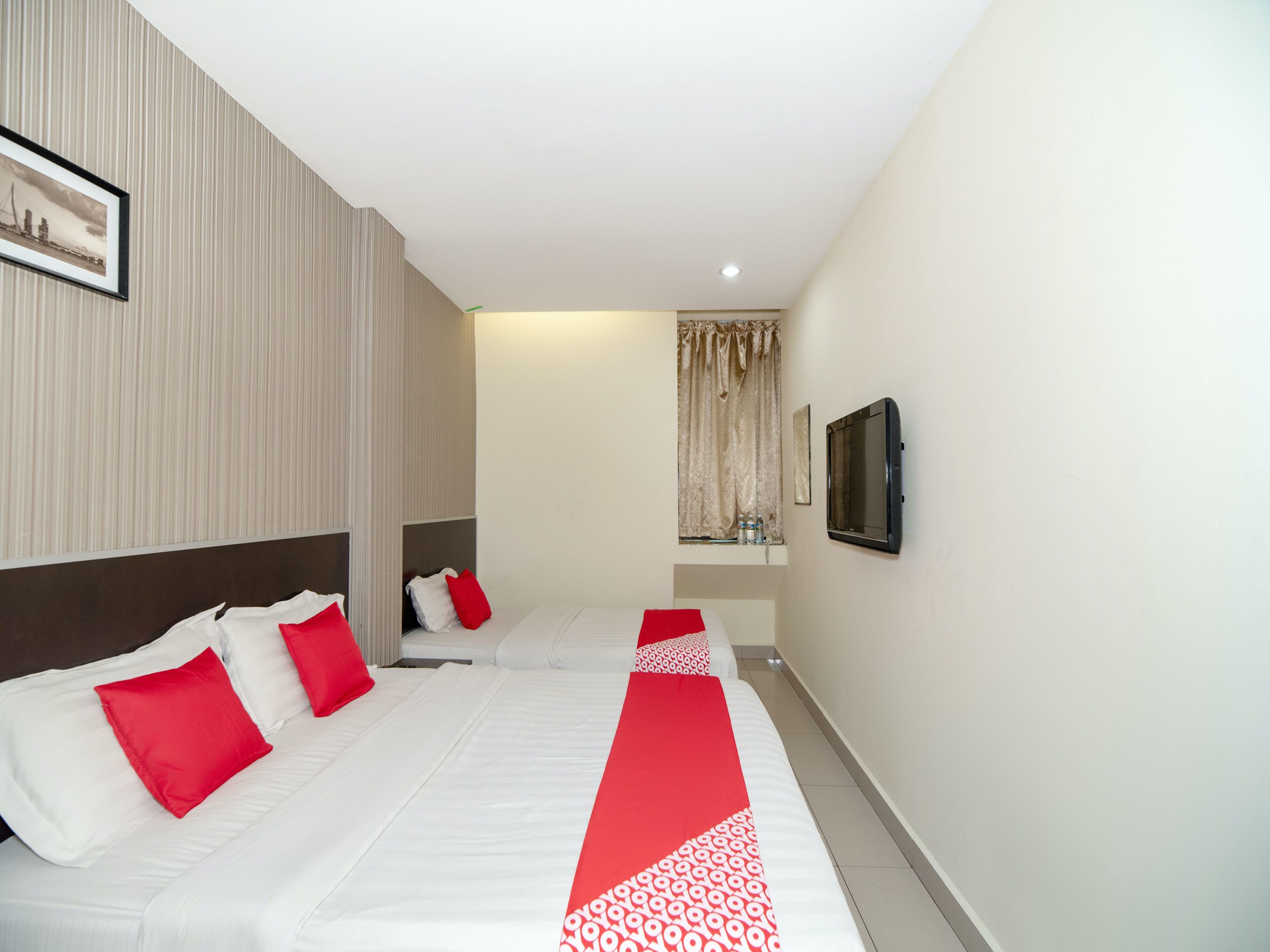 A hotel room with two beds, a television, and a framed picture on the wall.