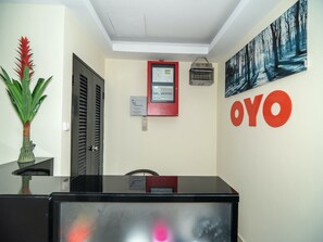 A reception desk with a digital display, a framed certificate, and a wall-mounted security camera. - OYO 89965 Stay Inn Ii (Kota Kinabalu)