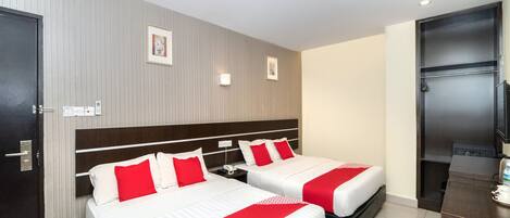 A hotel room with two beds, a minibar, a television, and a door.