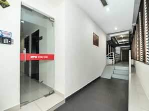 A hotel corridor with a glass door, a red sign reading "OYO STAY INN", and a staircase leading to an upper level. - OYO 89965 Stay Inn Ii (Kota Kinabalu)