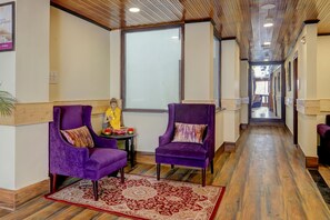 A hallway with purple chairs, a Buddha statue, and a red patterned rug. - Sumitel Sanderling, Darjeeling (Darjeeling)