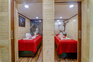 A spa room with two red-covered beds, wooden walls, and a poster advertising 'Aqua spa'. - Sumitel Sanderling, Darjeeling (Darjeeling)