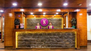 A reception desk with a stone facade, wooden paneling, and a logo above the counter.