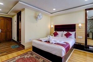 A hotel room with a bed, a wooden floor, a red and white patterned rug, a wooden door, and a stone wall. - Sumitel Sanderling, Darjeeling (Darjeeling)