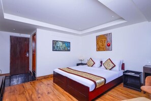 A modern hotel room with a large bed, a wooden floor, a door, and a painting on the wall. - Sumitel Sanderling, Darjeeling (Darjeeling)