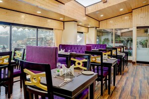 A restaurant with wooden ceiling and walls, purple seating, and tables set for dining. - Sumitel Sanderling, Darjeeling (Darjeeling)