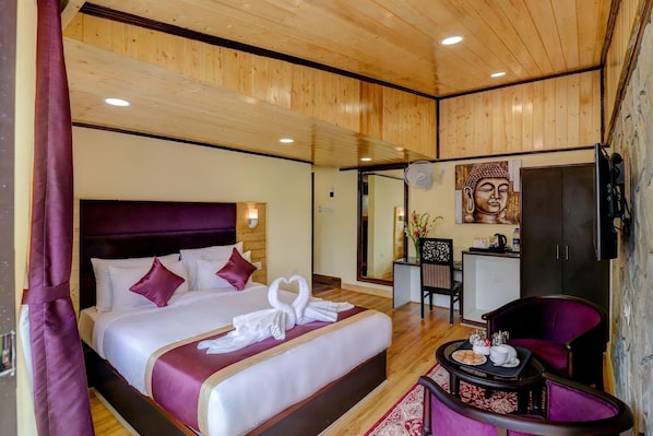 Habitación de hotel con una cama grande, un escritorio con silla, una estatua de Buda y un televisor.