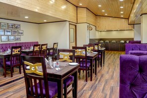 A dining area with wooden tables, purple upholstered chairs, and a buffet station. - Sumitel Sanderling, Darjeeling (Darjeeling)