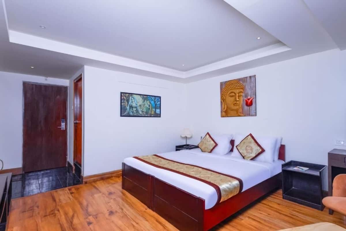 Una habitación de hotel moderna con una cama grande, suelo de madera, una puerta y un cuadro en la pared.