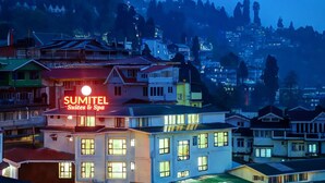A hotel with a prominent sign, multiple stories, and a view of surrounding buildings.