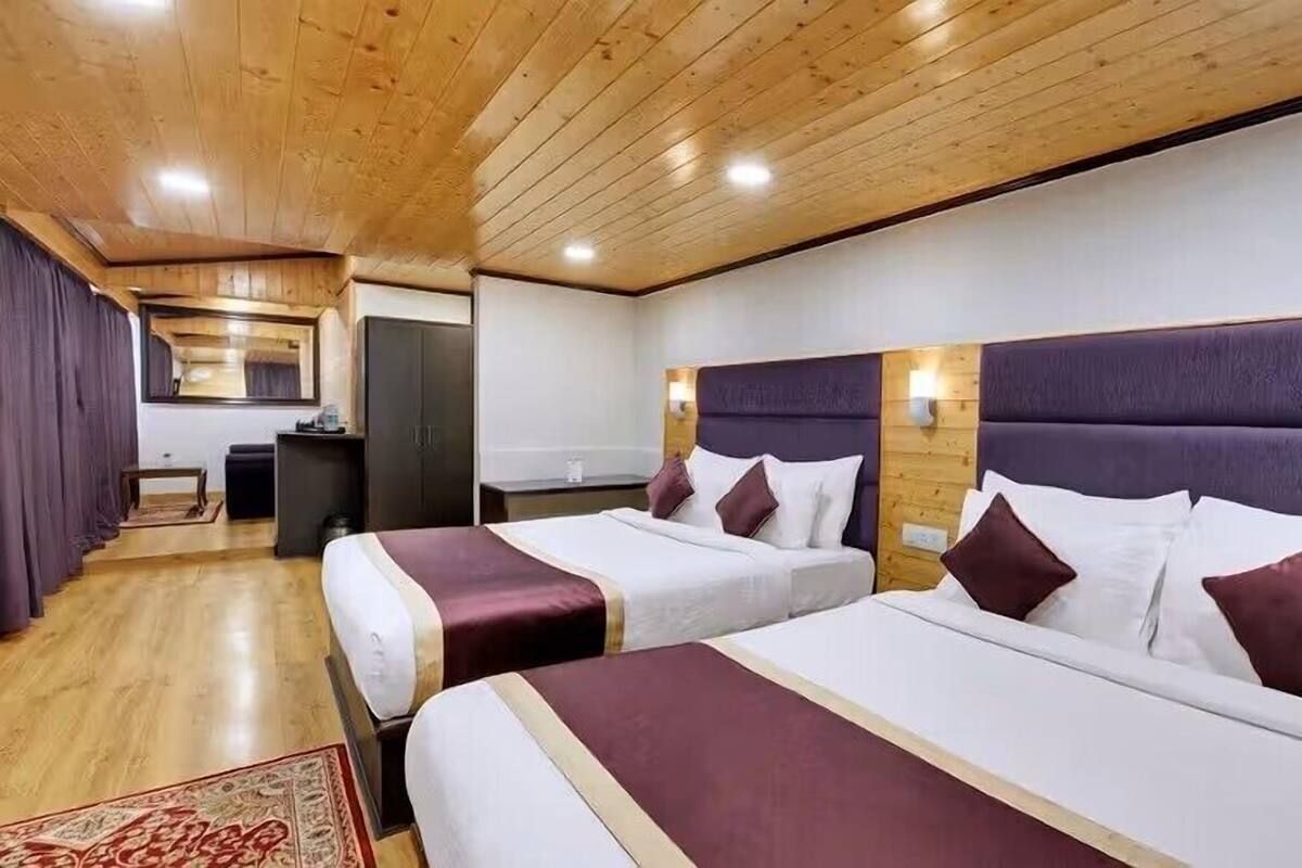 Habitación de hotel con dos camas, techo de madera y un pequeño escritorio con silla.