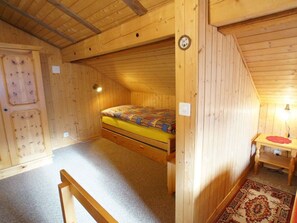 Une pièce en bois avec un lit superposé, une petite table et un tapis.