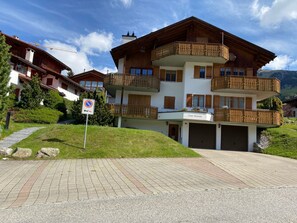 Un edificio a più piani con balconi, un cartello che indica divieto di parcheggio e una strada asfaltata.