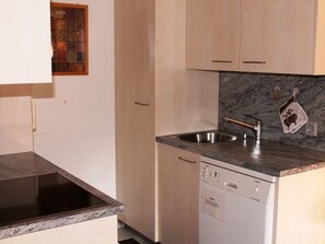 A compact kitchen with a built-in dishwasher, a stainless steel sink, and a granite countertop. - Casa Nual Stelzer, (Sedrun), 189.01 by Interhome (Sedrun)