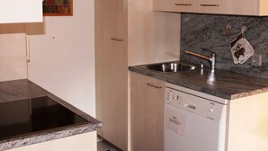 Una cocina con lavavajillas, pileta de acero inoxidable y estante para especias.