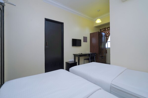 A hotel room with two beds, a desk, a TV, and a wardrobe.