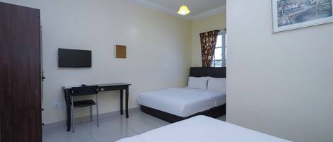 A hotel room with a bed, a desk, a chair, a television, and a window with curtains.