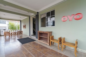 A room with a tiled floor, wooden furniture, a bench, and a wall with a sign.
