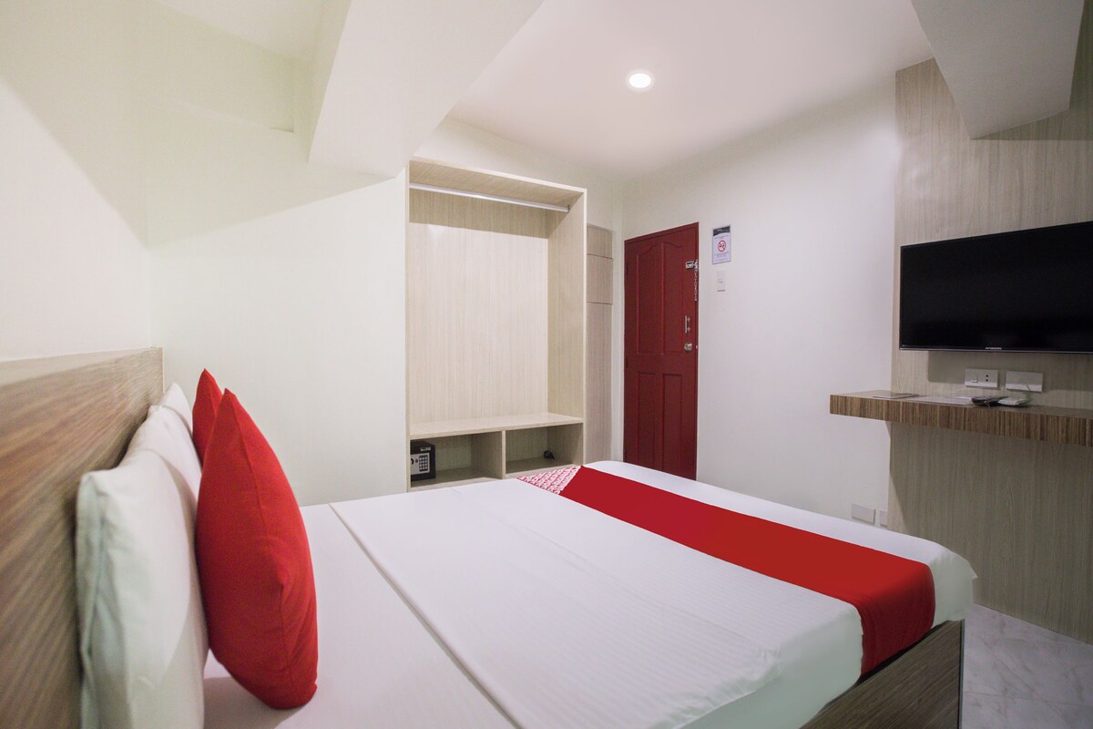 A hotel room with a bed, a TV, a wardrobe, and a mirror.