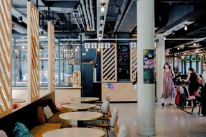 A café with round tables and a seating area with cushions. - Slo Hostel (Bordeaux)
