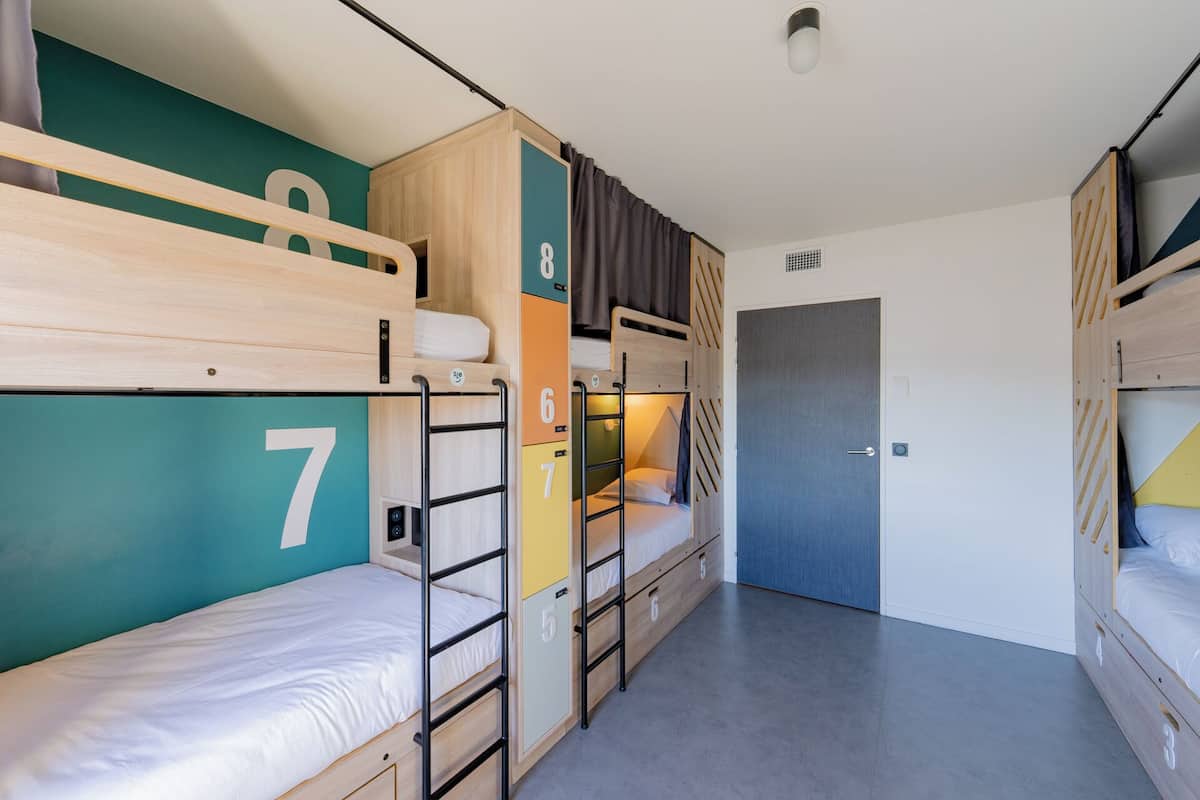 A compact dormitory room with bunk beds, a door, and a small closet.
