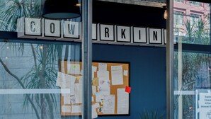 Un café avec un mur en verre, un tableau d’affichage et des tables à l’extérieur.