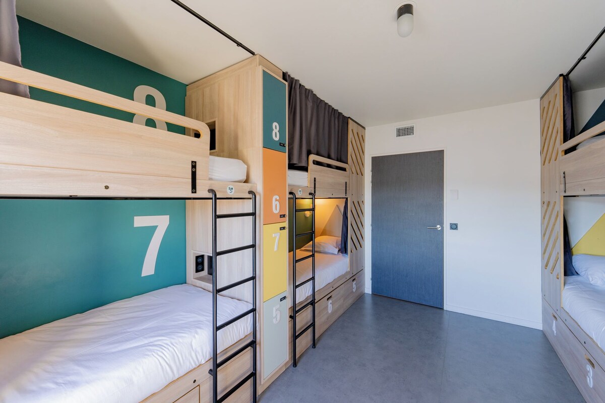 A compact dormitory room with bunk beds, a door, and a small closet.