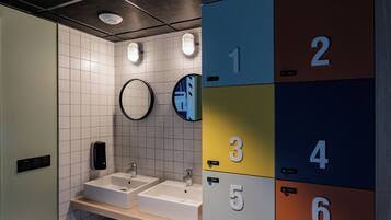 Un baño moderno con dos lavabos, un espejo y taquillas numeradas del 1 al 8.