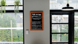 A café with a menu board, white chairs, and a view through large windows.