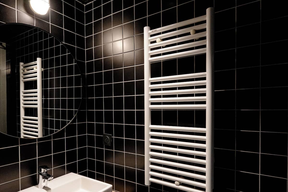A modern bathroom with a white sink, a mirror, and a towel rack.
