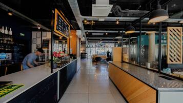Zona de bar moderna con barra, asientos y un panel con la carta.