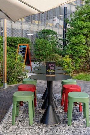 Et rundt bord med skamler, et skilt der siger 'HAPPY HOUR 18-20R' og en menu-tavle i baggrunden.