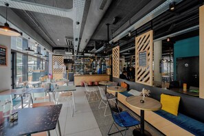 A modern cafe with seating areas, a bar, and a view of the street.