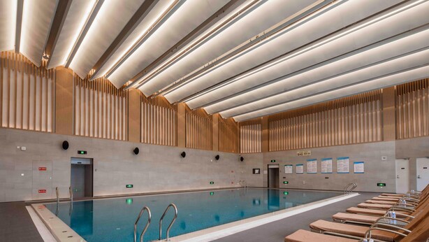 A swimming pool with a tiled floor, metal handrails, and lounge chairs with towels. - Crowne Plaza Beijing Badaling (Yanqing)