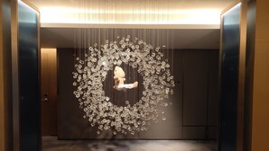 A modern interior with a central sculpture, a glass elevator, and a patterned floor. - Crowne Plaza Beijing Badaling (Yanqing)