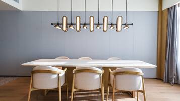 Uma sala de jantar moderna com uma mesa comprida, quatro cadeiras e uma luminária pendente singular.