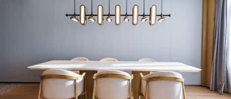 Un comedor moderno con una mesa larga, cuatro sillas y una lámpara colgante original.